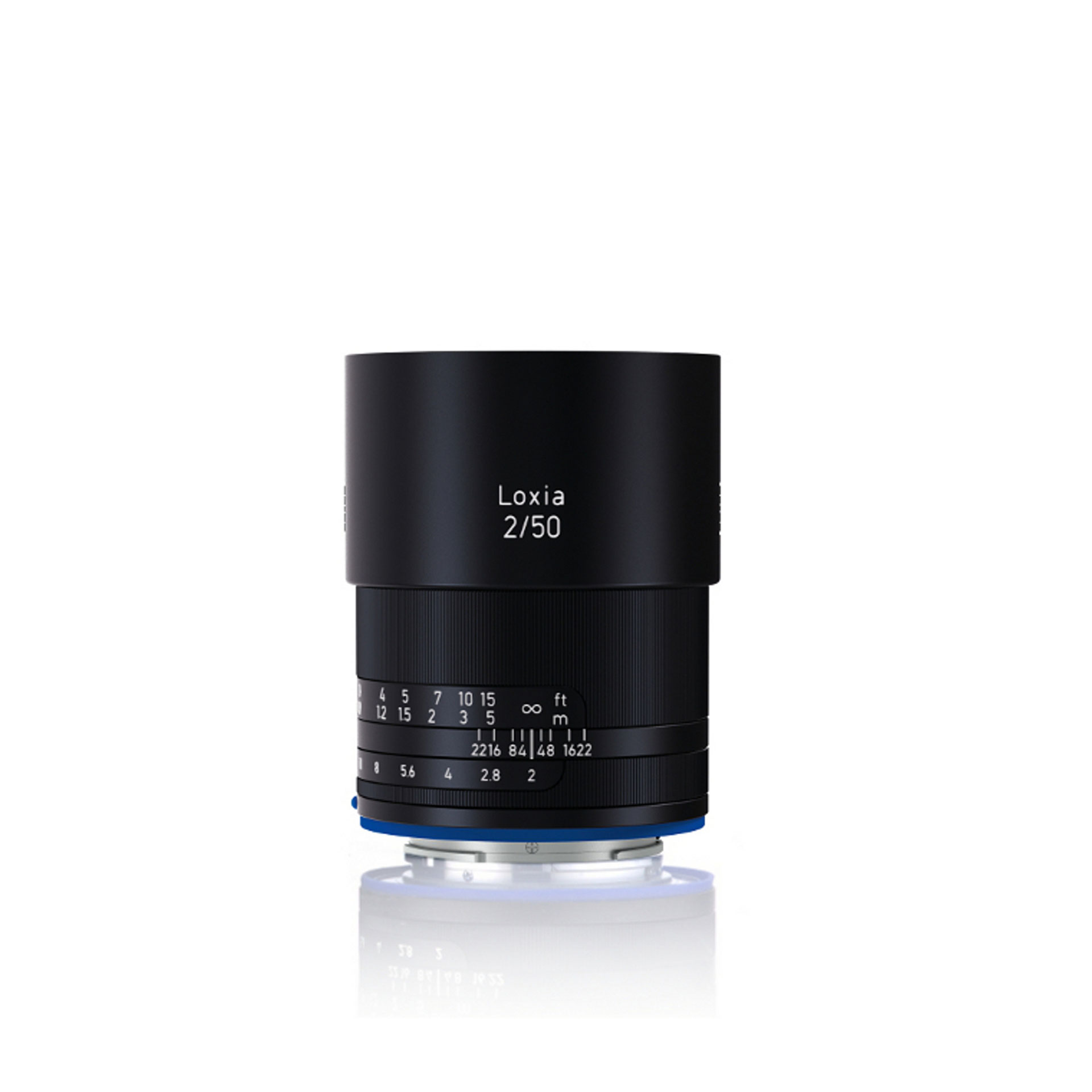 Black ZEISS Loxia 2/50 camera lens standing upright on a white reflective surface.