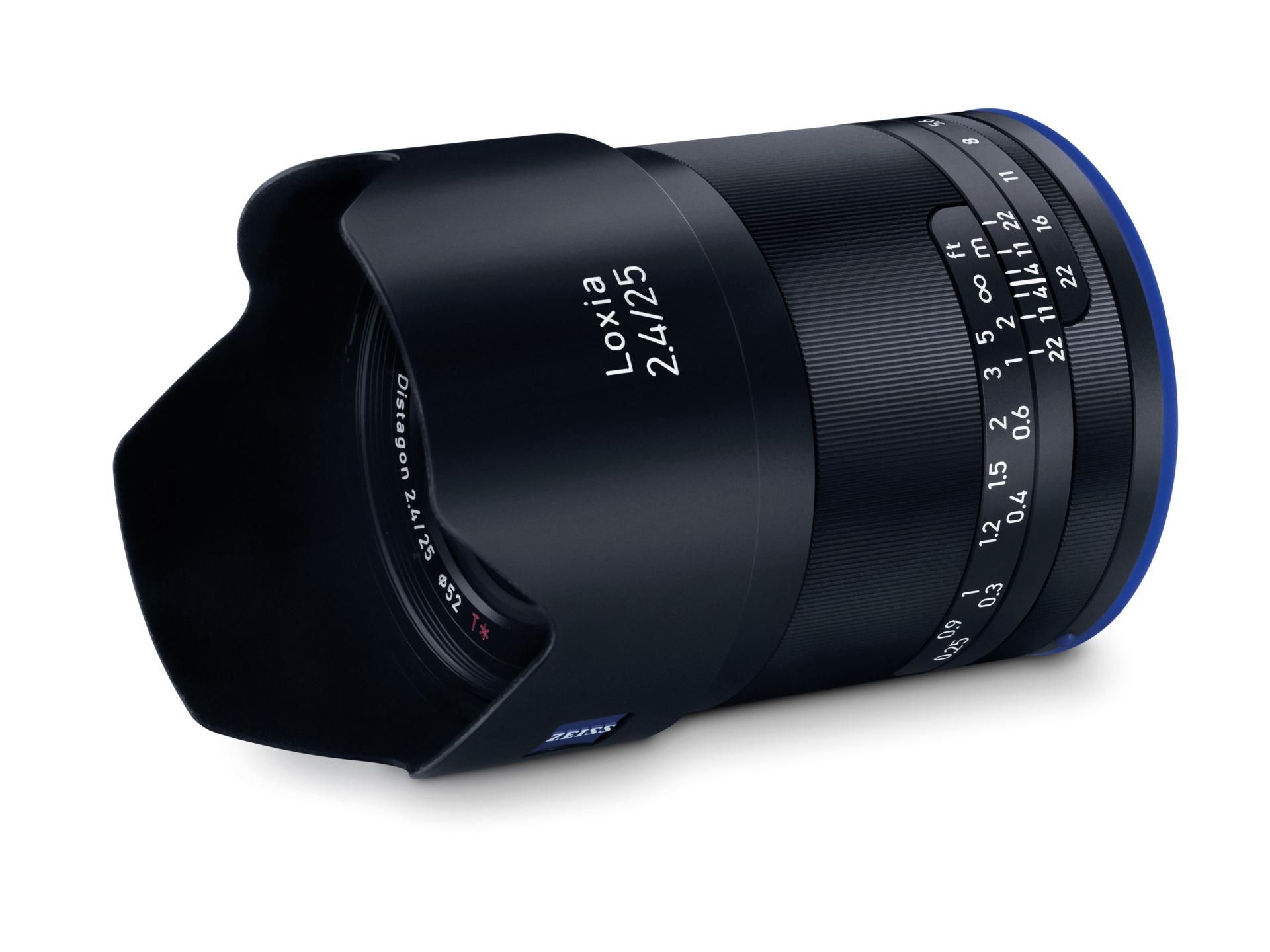 Close-up image of a ZEISS Loxia 2.4/25 camera lens featuring focus and aperture markings, a metal construction, and a built-in lens hood.