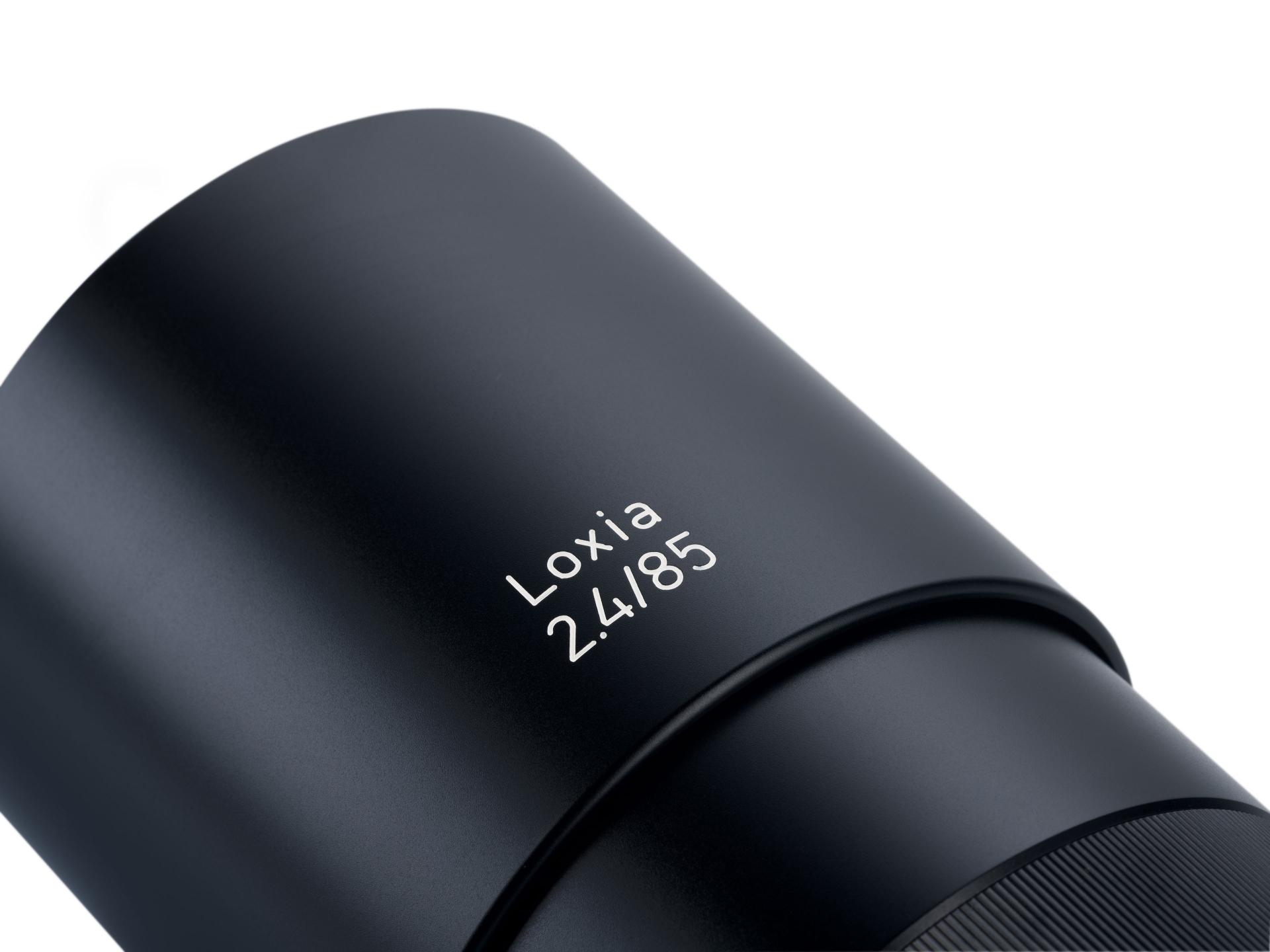 Close-up view of a ZEISS Loxia 2.4/85 camera lens in a sleek black finish.