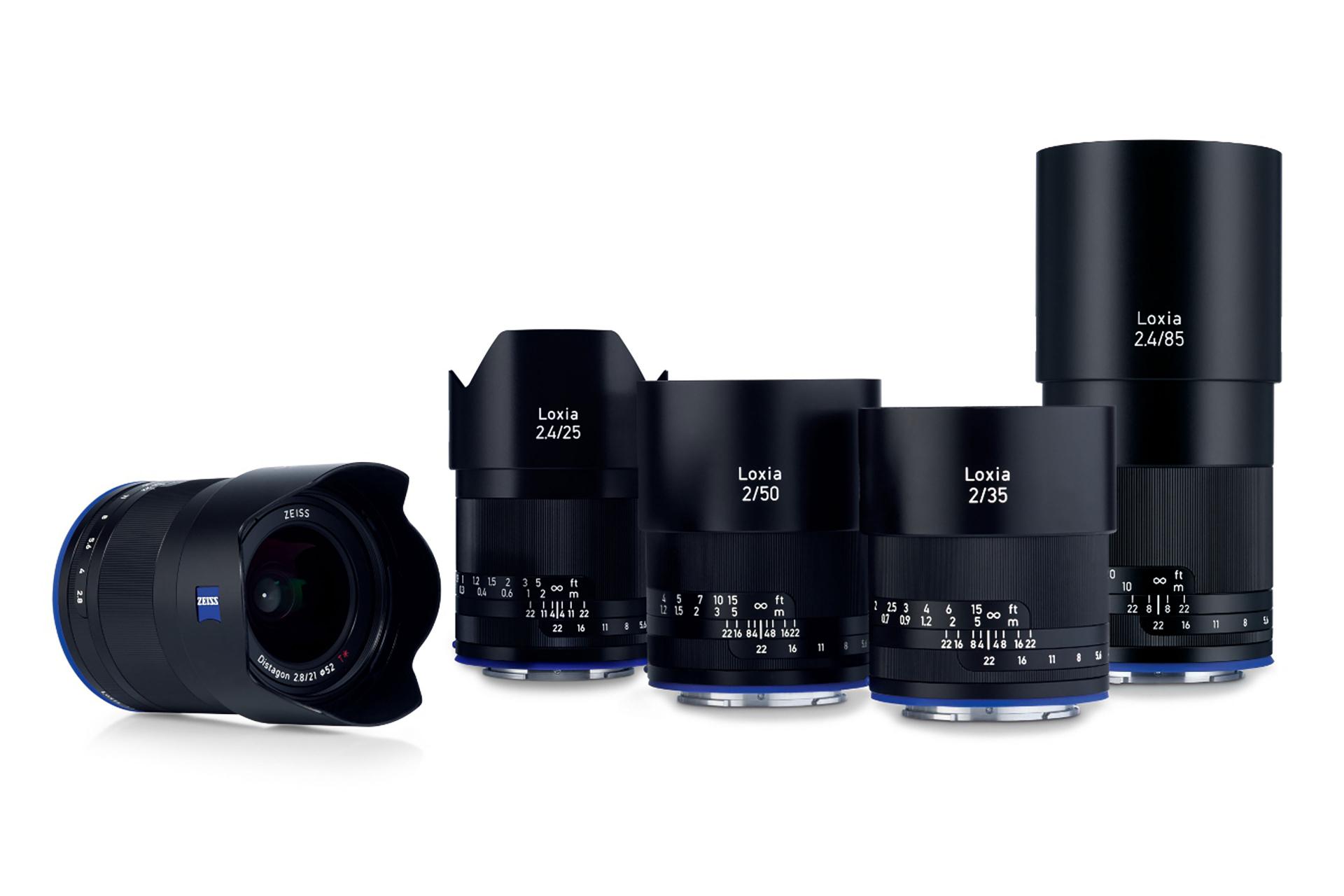 Five ZEISS Loxia camera lenses of varying focal lengths are displayed upright in a row, with one lens positioned horizontally in front.