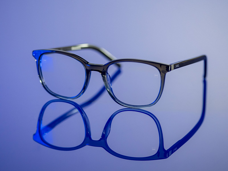 Bril met heldere glazen op een glimmend blauw oppervlak.