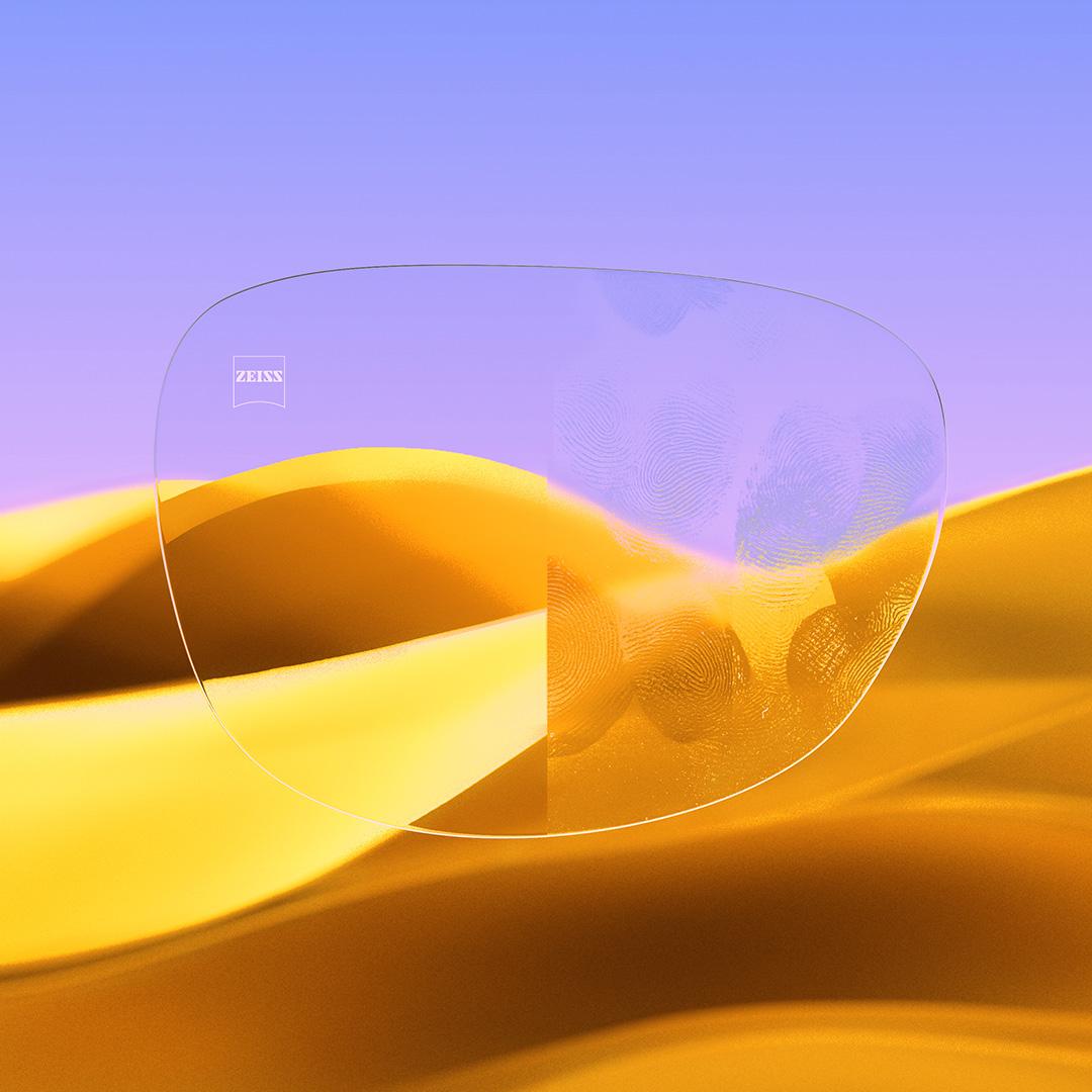 Een afbeelding met een gedeeld brillenglas waarvan de ene helft helder en schoon is dankzij ZEISS DuraVision Gold UV, terwijl op de andere helft vingerafdrukken te zien zijn.