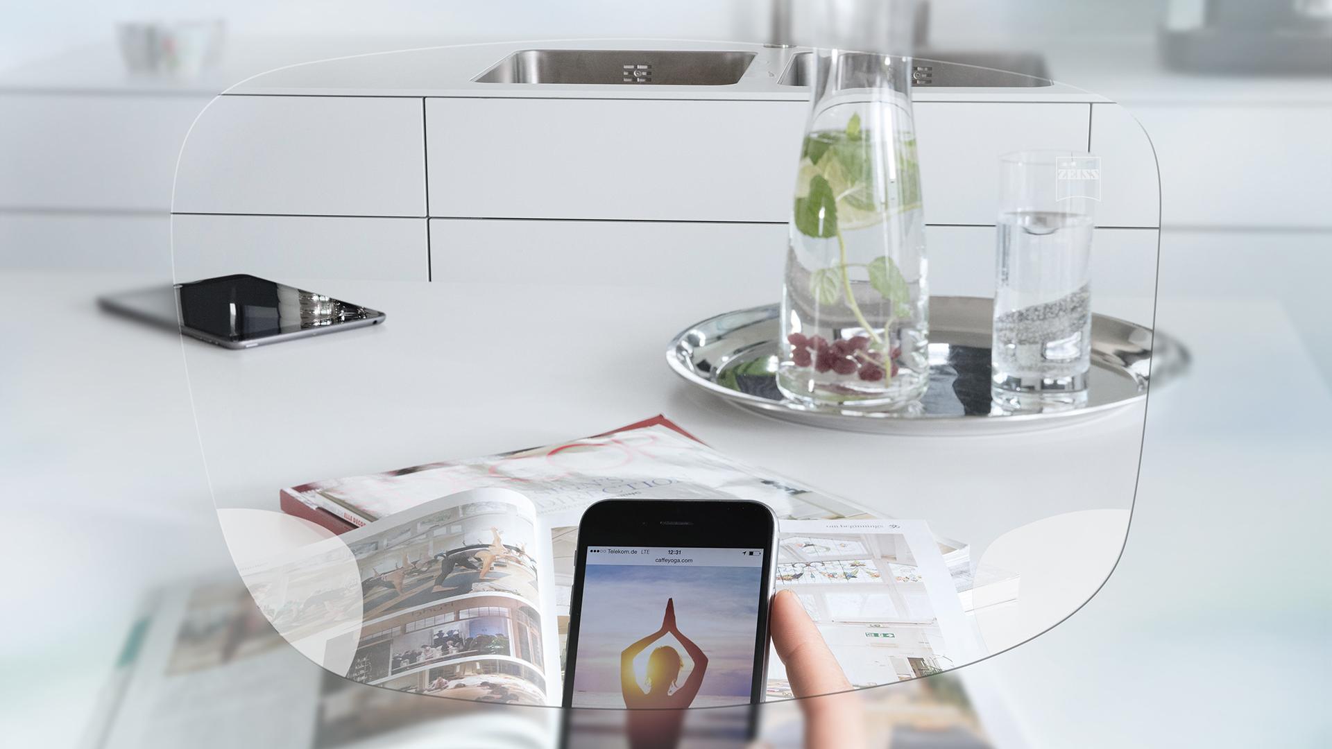 Zicht door een ZEISS Unifocaal EnergizeMe brillenglas bij een smartphone en keukentafel