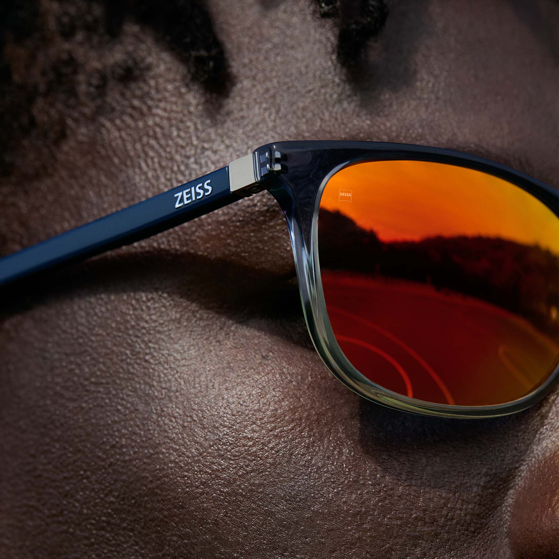 Close-up van een man die een ZEISS bril draagt met ZEISS DuraVision Mirror UV zonnebrilcoating in oranje.