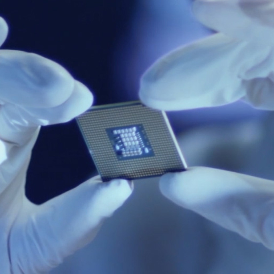 Een afbeelding van een microchip die wordt vastgehouden door een persoon met laboratoriumhandschoenen. 