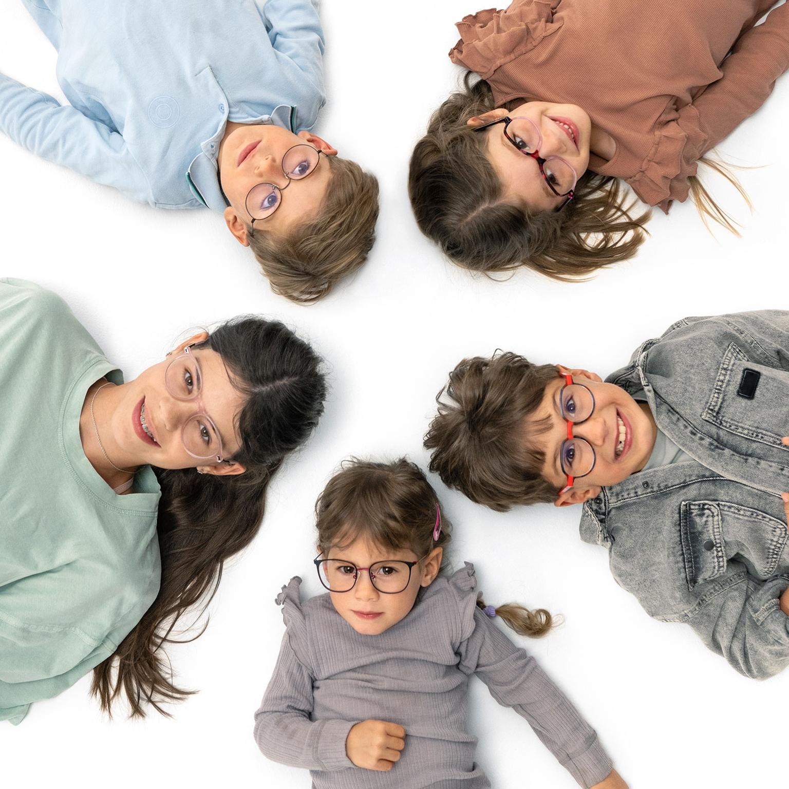 Groep brildragende kinderen die vrolijk in een kring op de grond liggen