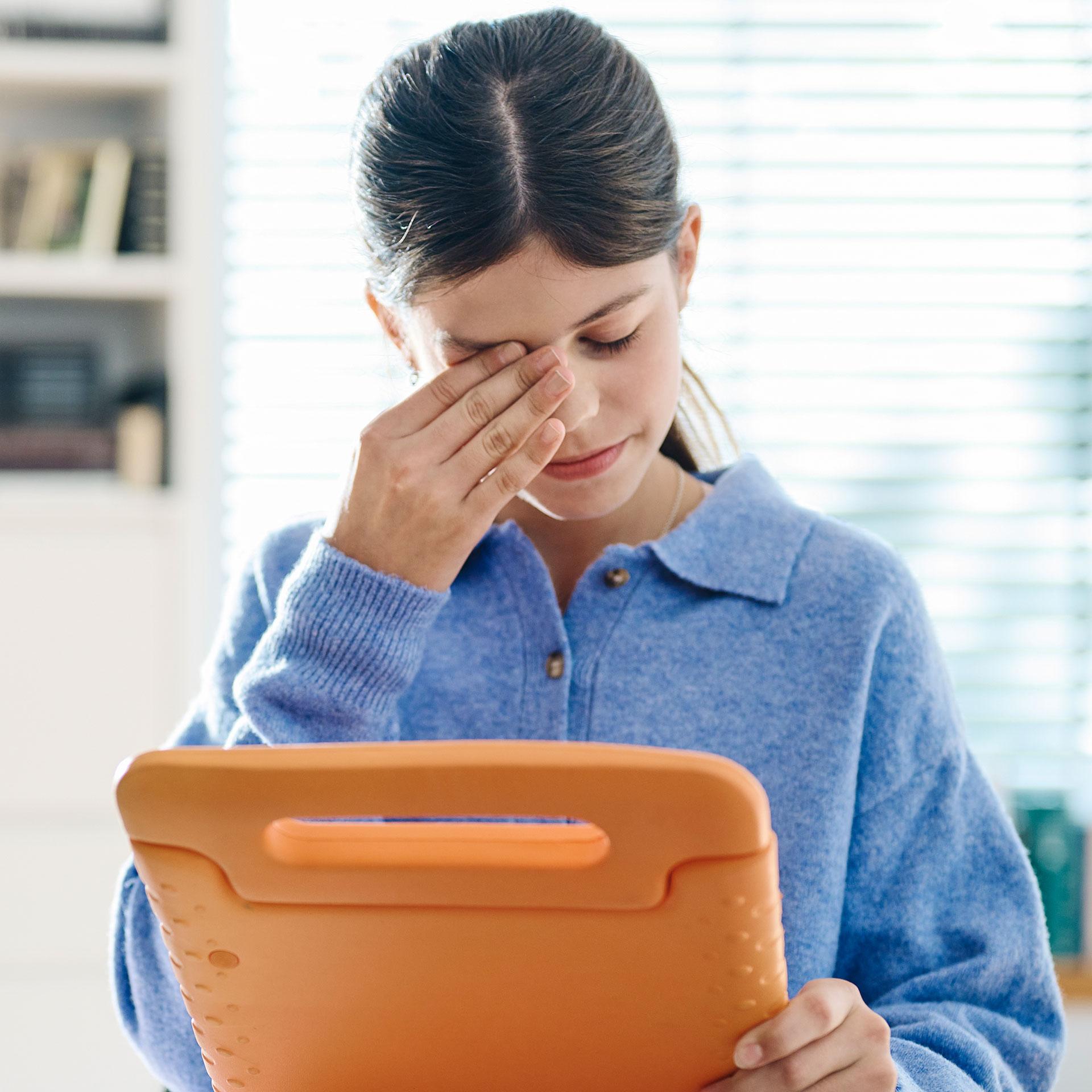 Meisje met tablet die haar hand tegen het gezicht houdt