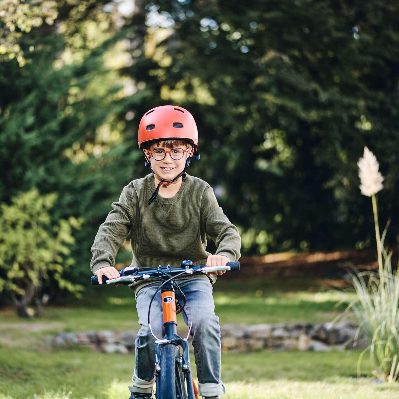 Lachende jongen met bril buiten op de fiets