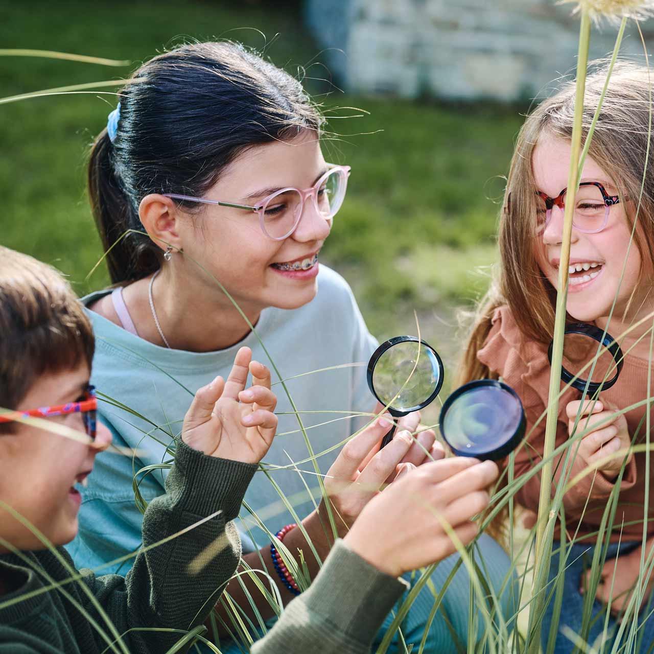 Groep kinderen met bril en vergrootglazen die buitenspelen en plezier hebben