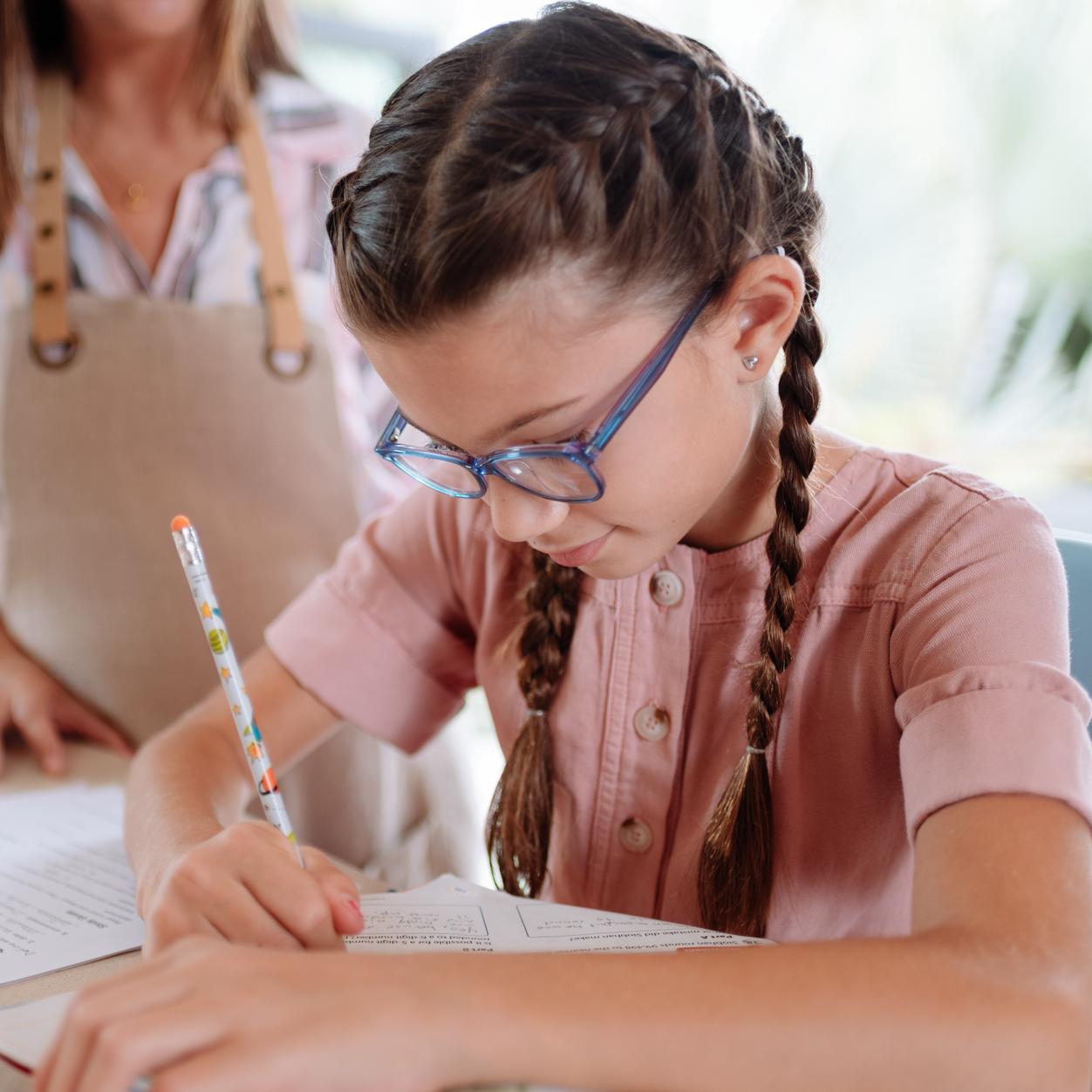 Meisje met bril schrijft met pen