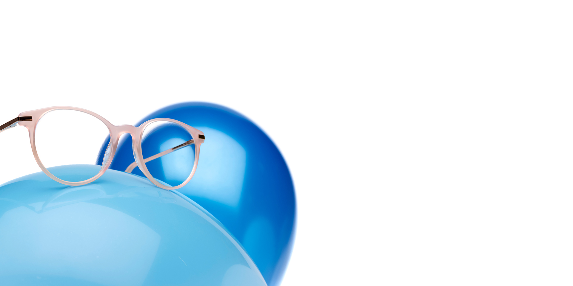 ZEISS MyoCare brillenglazen in een beige roze montuur worden getoond op een lichtblauwe ballon. Op de achtergrond staat nog een iets donkerdere blauwe ballon.